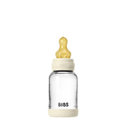 Clear baby bottle with beige cap and heart-shaped nipple on a white background