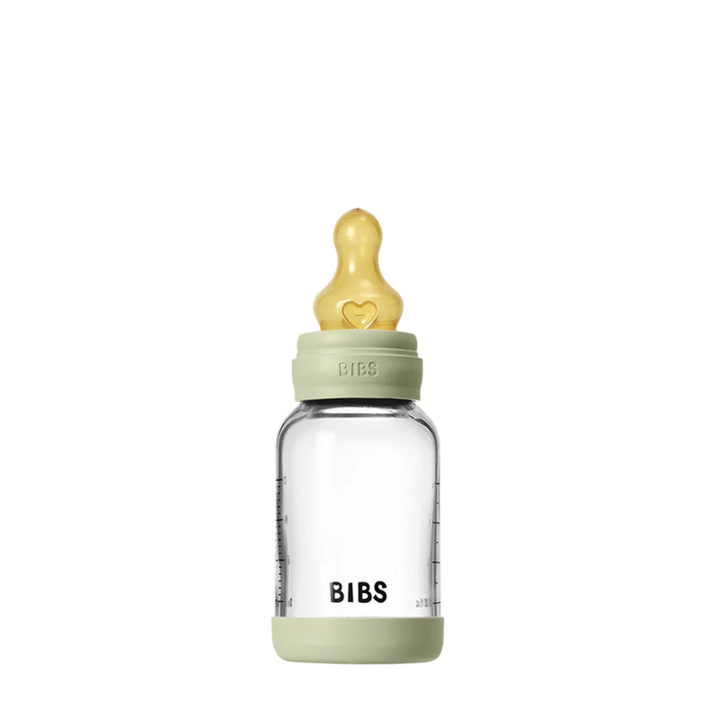 Clear baby bottle with green cap and base on a white background