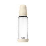 Clear baby bottle with beige cap and base on a white background