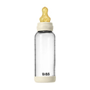 Clear baby bottle with beige cap and base on a white background