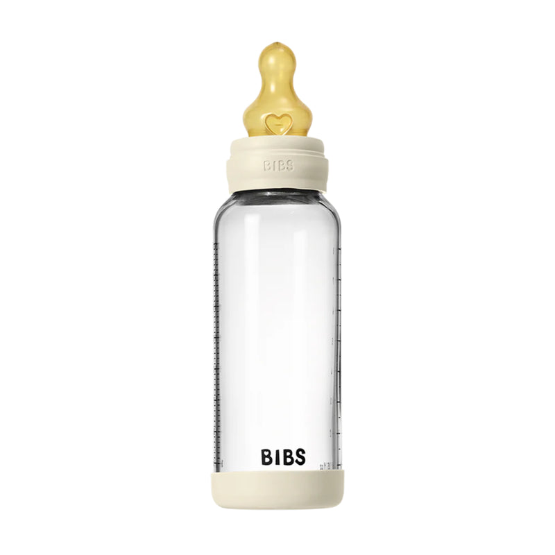 Clear baby bottle with beige cap and base on a white background