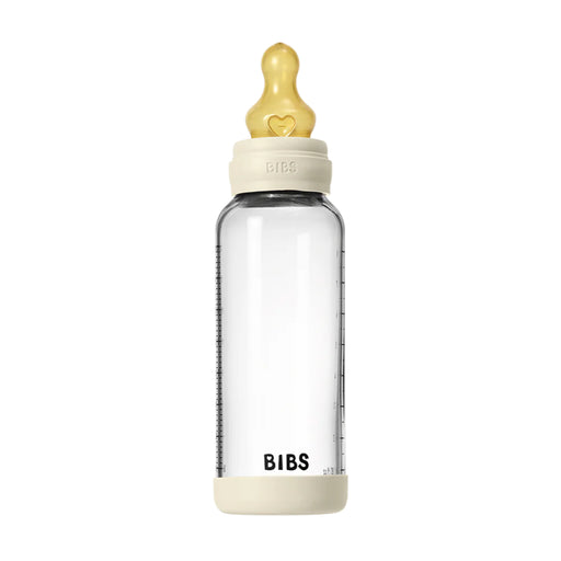 Clear baby bottle with beige cap and base on a white background