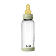 Clear baby bottle with green cap and base on a white background