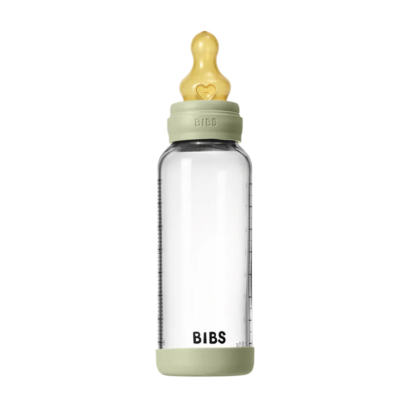 Clear baby bottle with green cap and base on a white background