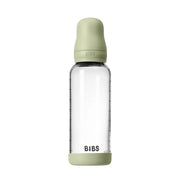 Clear baby bottle with green cap and base on a white background