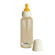 Clear baby bottle with orange nipple and white base on a beige background