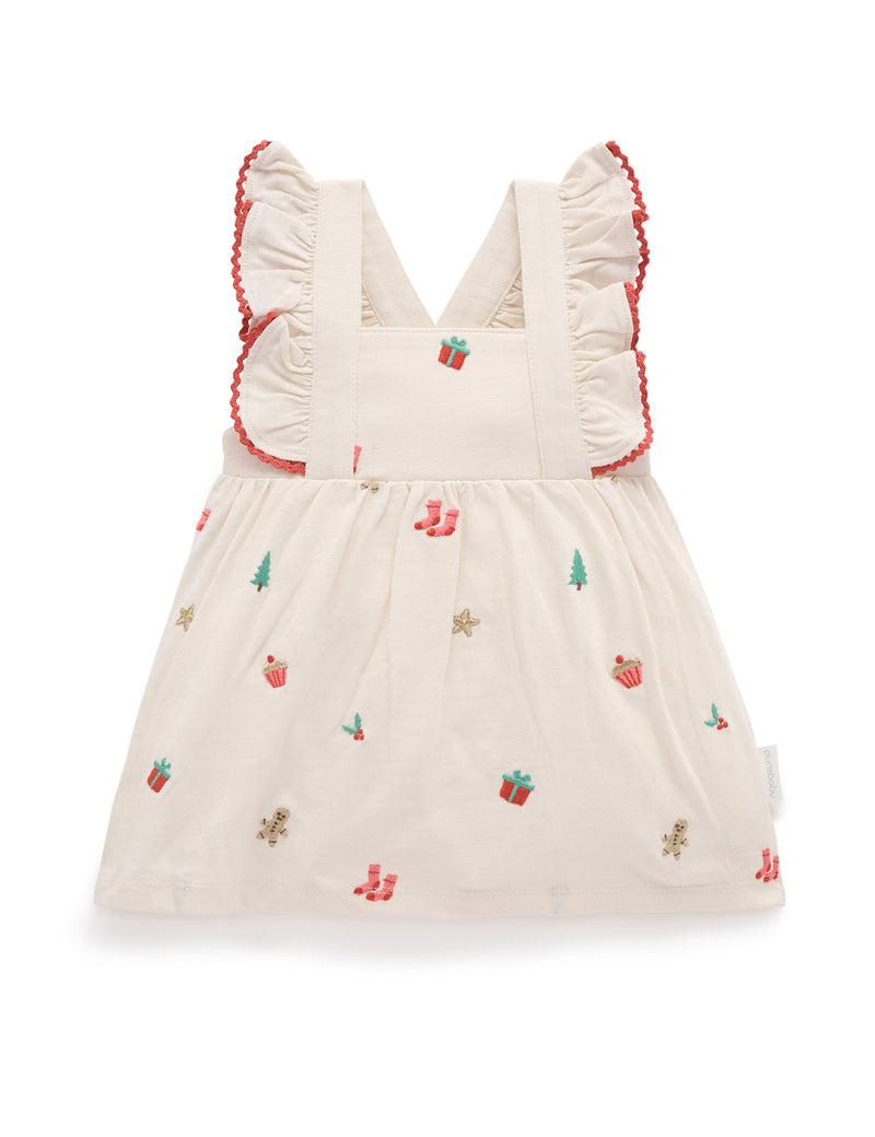 White dress with red trim and embroidered designs on a white background