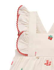 Close-up of a baby dress with ruffled details and embroidered designs on a white background